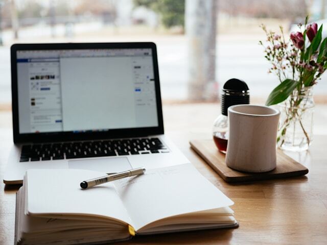 macbook pro near white open book and a coffe mug in the left